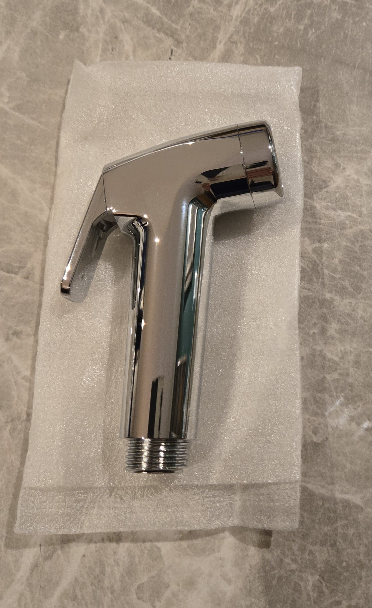 Angled view of handheld bidet sprayer showing nozzle and trigger design